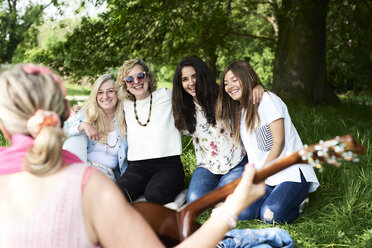 Gruppe von Frauen mit Gitarre, die sich bei einem Picknick im Park amüsieren - IGGF01008