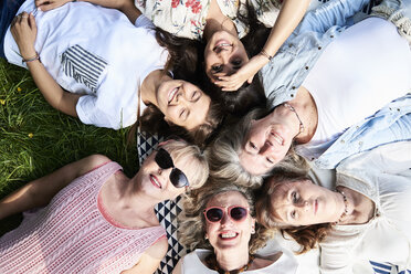 Draufsicht auf eine fröhliche Gruppe von Frauen, die auf einer Wiese liegen - IGGF01014