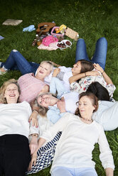 Fröhliche Gruppe von Frauen, die auf einer Decke auf einer Wiese liegen - IGGF01015