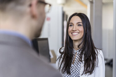 Geschäftsmann und lächelnde Geschäftsfrau im Gespräch in einer modernen Fabrik - DIGF06517