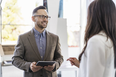 Smiling businessman and busineswoman talking in a modern factory - DIGF06522