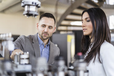 Businessman and businesswoman examining workpieces in factory - DIGF06532