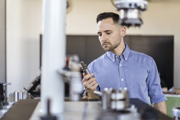 Geschäftsmann bei der Prüfung eines Werkstücks in einer Fabrik - DIGF06539