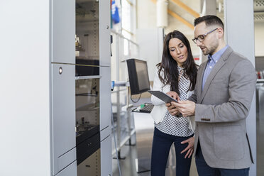 Businessman and businesswoman with talking in modern factory - DIGF06561