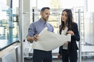 Businessman and businesswoman discussing plan in modern factory - DIGF06579