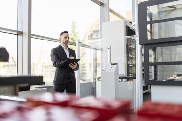 Geschäftsmann hält Ordner in einer modernen Fabrik - DIGF06591