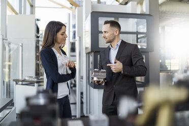 Businessman and businesswoman discussing workpiece in factory - DIGF06595