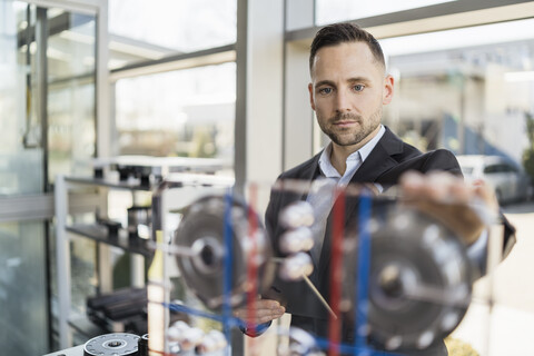 Porträt eines Geschäftsmannes mit Blick auf eine Maschine in einer modernen Fabrik, lizenzfreies Stockfoto