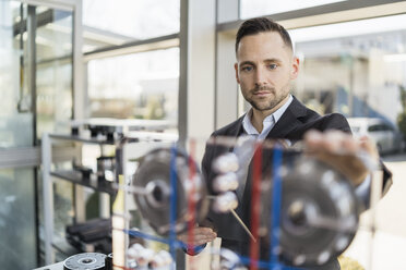 Porträt eines Geschäftsmannes mit Blick auf eine Maschine in einer modernen Fabrik - DIGF06604