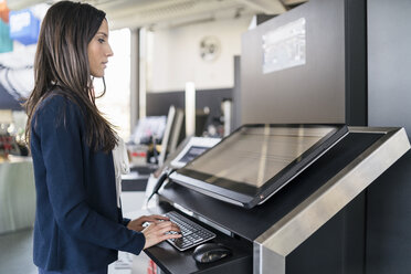 Geschäftsfrau bedient Maschine in einer modernen Fabrik - DIGF06611