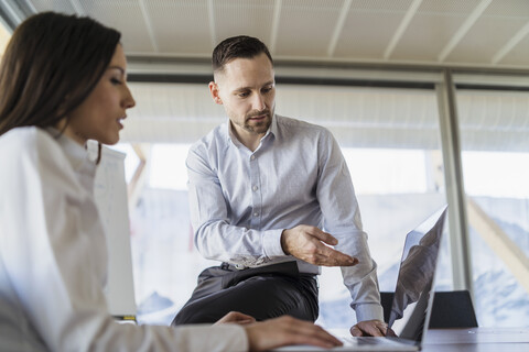 Geschäftsmann und Geschäftsfrau mit Laptop bei der Arbeit im Büro, lizenzfreies Stockfoto