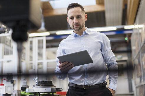 Geschäftsmann mit Tablet an einer Maschine in einer modernen Fabrik - DIGF06645