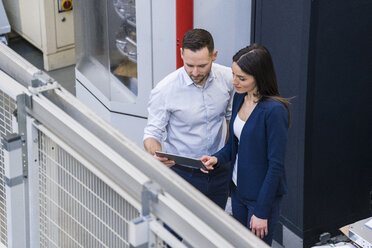 Geschäftsmann und Geschäftsfrau mit Tablet im Gespräch in einer modernen Fabrik - DIGF06648