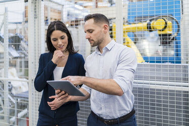 Geschäftsmann und Geschäftsfrau mit Tablet im Gespräch in einer modernen Fabrik - DIGF06649