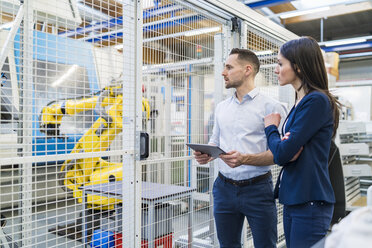 Geschäftsmann und Geschäftsfrau mit Tablet im Gespräch in einer modernen Fabrik - DIGF06659