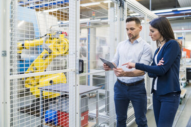 Businessman and businesswoman with tablet talking in modern factory - DIGF06660