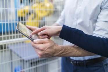 Close-up of businessman and businesswoman using tablet in modern factory - DIGF06661