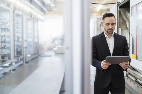 Geschäftsmann mit Tablet in einer modernen Fabrik, lizenzfreies Stockfoto