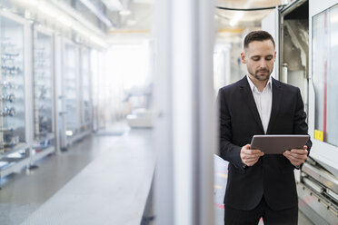 Businessman using tablet in a modern factory - DIGF06666