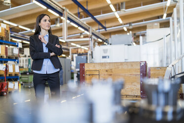 Businesswoman standing in a factory looking around - DIGF06684