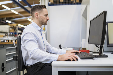 Geschäftsmann mit Computer am Schreibtisch in einer Fabrik - DIGF06686