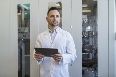 Man with tablet wearing lab coat in modern factory - DIGF06708
