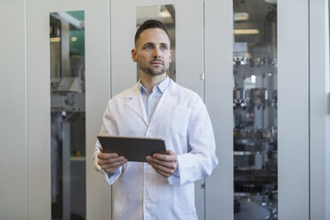 Mann mit Tablet im Laborkittel in einer modernen Fabrik - DIGF06708