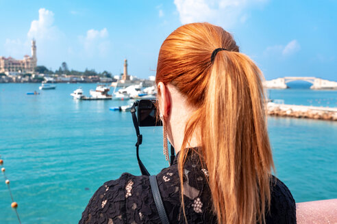 Weibliche Touristin mit roten Haaren fotografiert über dem Meer in Richtung Montaza-Palast, Rückansicht, Alexandria, Ägypten - CUF50147