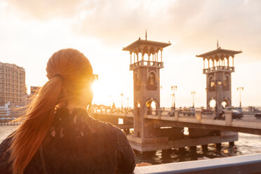 Weibliche Touristin mit roten Haaren schaut bei Sonnenuntergang über die Stanley-Brücke, Rückansicht, Alexandria, Ägypten - CUF50149