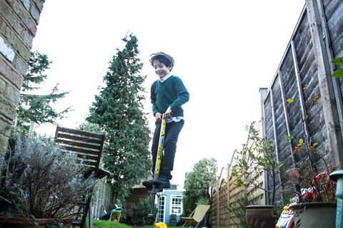 Boy jumping on pogo stick in garden stock photo