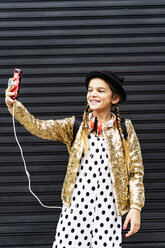 Porträt eines lächelnden Mädchens mit Hut und goldener Paillettenjacke, das ein Selfie mit seinem Smartphone macht - ERRF00891