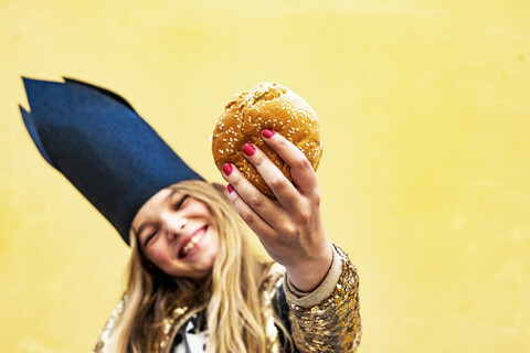 Hand eines lächelnden Mädchens, das einen Hamburger hält, Nahaufnahme, lizenzfreies Stockfoto