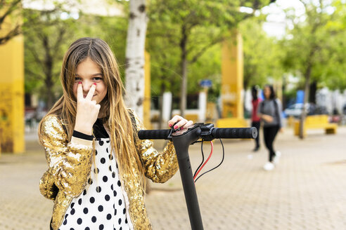 Portrait of smiling girl with scooter wearing golden sequin jacket - ERRF00936