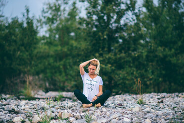 Woman stretching on bed of stones, Banff, Canada - ISF21092