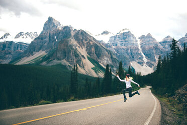 Frau springt auf der Straße in die Luft, Jasper, Kanada - ISF21094