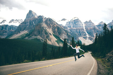 Woman jumping in mid air on road, Jasper, Canada - ISF21094