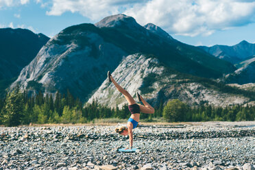 Frau macht Handstand auf einem Feld von Steinen, Jasper, Kanada - ISF21104