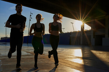 Freunde joggen im Sportstadion bei Sonnenuntergang - CUF50271