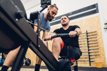 Personal Trainer arbeitet mit einem Mann mit Behinderung an einem Rudergerät - CUF50335