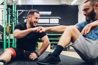 Personal Trainer und Mann mit Behinderung unterhalten sich im Fitnessstudio - CUF50356