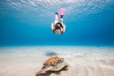 Woman swimming towards green sea turtle, Curacao - CUF50483