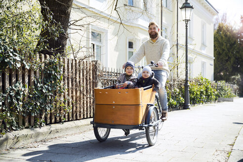 Happy father with two children riding cargo bike in the city - MAEF12831