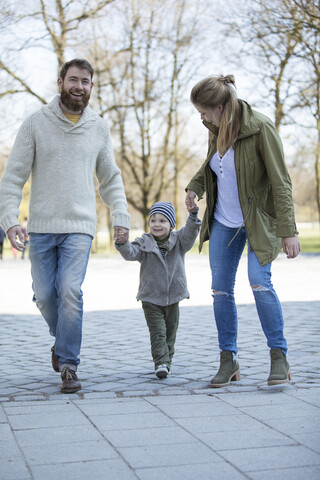 Glückliche Eltern gehen Hand in Hand mit ihrem Sohn, lizenzfreies Stockfoto