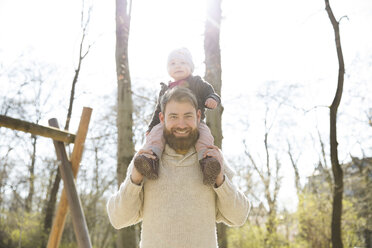 Porträt eines glücklichen Vaters, der seine Tochter im Park auf den Schultern trägt - MAEF12842