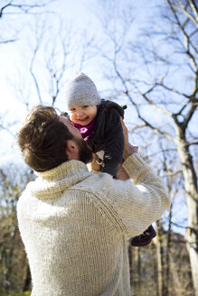 Father lifting up happy daughter in park - MAEF12848