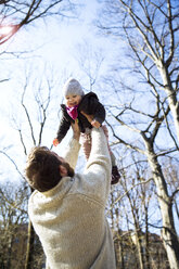 Father lifting up happy daughter in park - MAEF12849