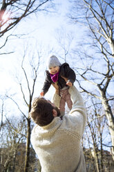Father lifting up happy daughter in park - MAEF12850