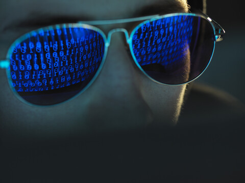 Cyberkriminalität, Spiegelung in der Brille eines Virus, der einen Computer hackt, Nahaufnahme des Gesichts, lizenzfreies Stockfoto