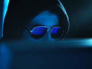 Cyberkriminalität, Spiegelung in der Brille eines Virus, der einen Computer hackt, Nahaufnahme des Gesichts - ABRF00371
