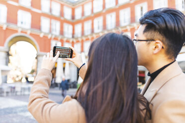 Spain, Madrid, young couple taking a smartphone picture in the city - WPEF01479